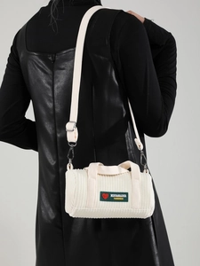 Fashionable cream corduroy barrel bag shown on model with shoulder strap and heart detail