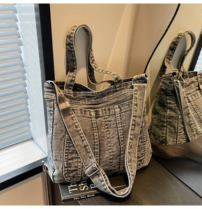 Detail of grey washed denim tote with quilted stitching and adjustable shoulder strap