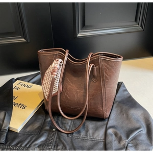 Detailansicht der braun strukturierten Kunstledertasche mit schickem Seidenschal-Akzent