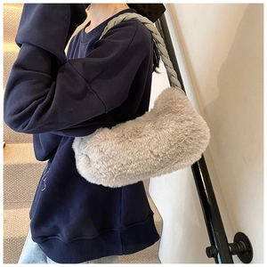 Gros plan du sac bandoulière en peluche gris chaud avec une sangle tressée sur l'épaule