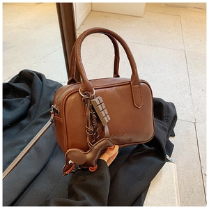Close-up of deep brown leather boston bag with chocolate and puppy charms and zipper detail