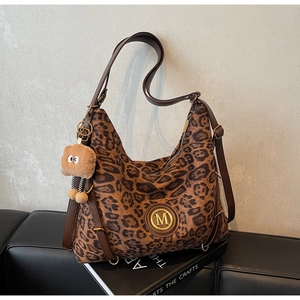 Detailed shot of leopard print tote bag featuring a golden M logo and fuzzy charm