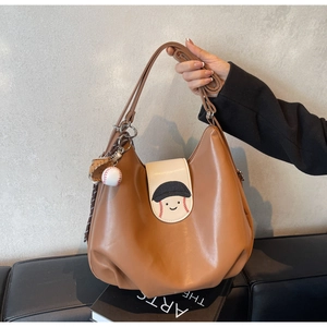 Detail of a brown leather tote with a baseball embroidered flap and creative charms