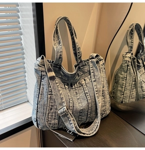 Detailed view of washed denim tote bag with metal buckles and adjustable strap