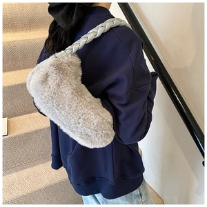 Détail du sac à épaule en fausse fourrure grise avec bandoulière tissée porté sur un sweat