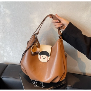 Close-up of caramel leather bag with baseball embroidery and miniature glove charms