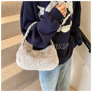 Détail du sac à bandoulière en peluche beige avec poignée tressée sur modèle