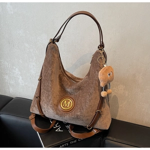 Close-up of vintage brown corduroy tote bag with leather trim and gold M logo detail