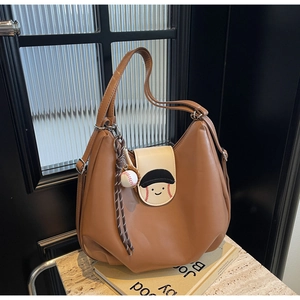 Detailed view of brown hobo bag with cartoon smiley face and mini baseball charm