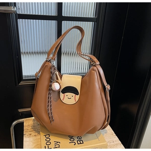 Detail of caramel brown baseball tote with decorative charms on a marble tabletop