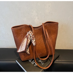 Detail der dunkelbraunen Leder-Shopper-Tasche mit elegantem Seidentuch am Schultergurt