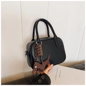 Close-up of black leather Boston bag featuring dachshund and chocolate bag charms
