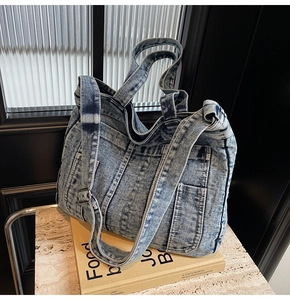 Close-up of blue denim tote bag featuring vintage wash texture and external pockets