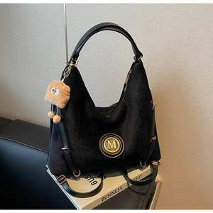 Detail of black velvet hobo bag with gold M logo and cute toast plush charm on books
