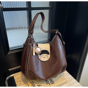 Close-up of brown matte leather tote with cartoon baseball patches and hanging charms