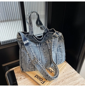 Detail of vintage washed denim tote bag showing multi-pocket design and adjustable strap