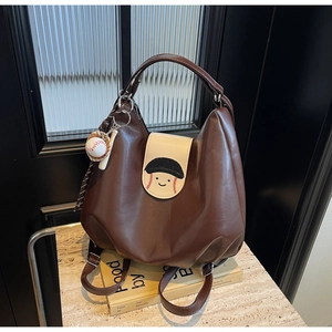 Detail of vintage brown backpack with baseball embroidery and a miniature charm