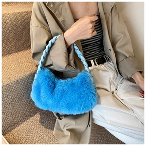 Gros plan d'un sac à main en peluche bleu vif avec une poignée en cuir tressé pour l'hiver