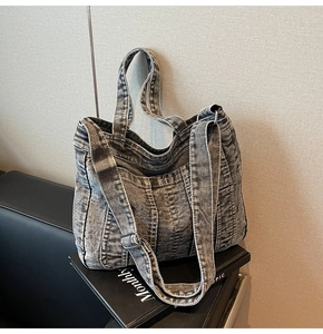 Detail of grey washed denim tote bag featuring adjustable shoulder strap and multiple pockets
