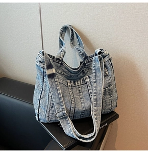 Detail shot of blue denim tote bag showing vintage stitching and metal strap buckle
