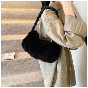 Détail du sac bandoulière en peluche noire avec sangle en cuir tressé sur un mannequin