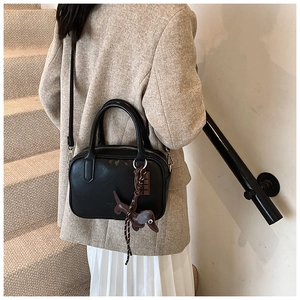 Detailed view of a black vintage Boston bag with a dog-shaped charm on a model