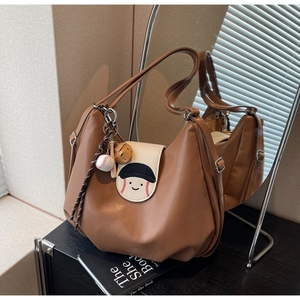 Detail of vintage brown leather tote bag featuring baseball embroidery and themed charms