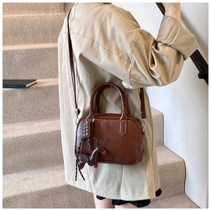 Detail of a brown vintage Boston bag featuring a pony charm and a crossbody strap