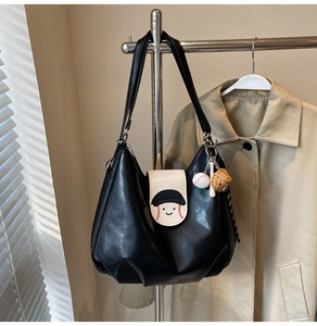 Detail of black PU leather tote with baseball smile embroidery and miniature sports charms