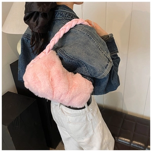 Détail du sac à épaule rose en peluche avec anse tressée sur une veste denim
