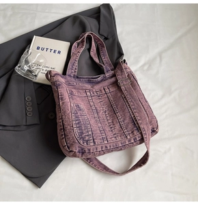 Detail of vintage washed denim tote bag with multiple pockets and adjustable shoulder strap