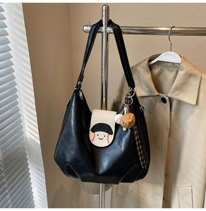 Detail of black tote bag with baseball-themed cartoon flap and themed charms on a hanger