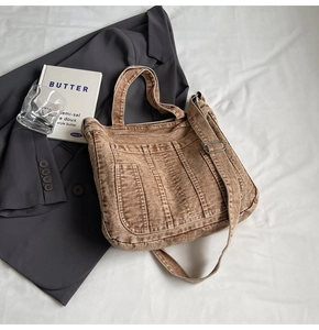 Detail of vintage washed denim tote bag with adjustable strap and rustic brown texture