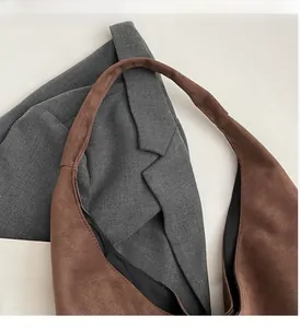 Détail de la texture en daim marron doux et de la bandoulière robuste du sac hobo