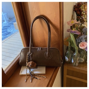 Detail of dark brown baguette bag with dual zippers and decorative teddy bear charm
