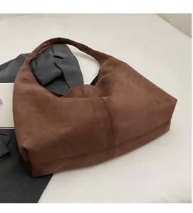 Gros plan d'un grand sac hobo en daim marron avec bandoulière large et surpiqûres