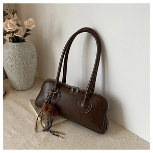 Close-up of brown baguette bag with dual zippers and cute teddy bear charm decoration