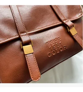 Close-up of brown faux leather tote bag with FREE 1981 COLOR embossed logo and gold buckle
