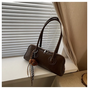 Detail of dark brown leather baguette bag with a cute plush bear charm and double zipper