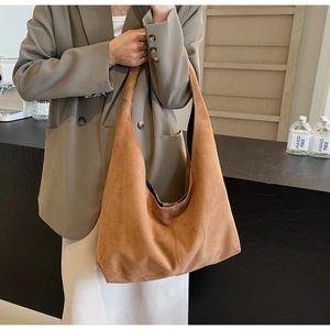 Detailed texture of brown suede tote bag featuring middle seam and wide shoulder strap