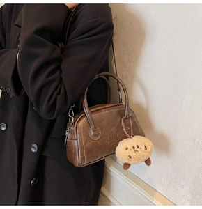 Detail der dunkelbraunen Retro-Bowlingtasche mit Kontrastnaht und Plüschtier-Anhänger