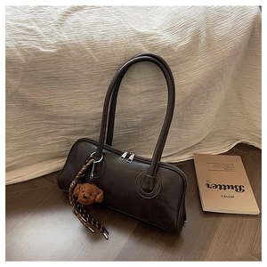 Detail of dark brown baguette bag with double silver zippers and a plush bear charm