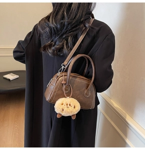 Detailansicht der braunen Bowling-Tasche mit hellen Nähten und Plüsch-Anhänger