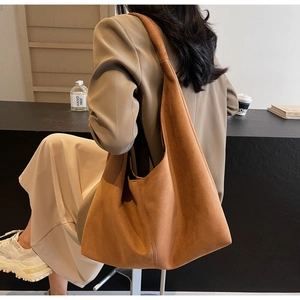 Detail of a large brown suede tote bag showing matte texture and minimalist shoulder style