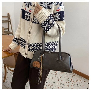 Detail view of dark brown faux leather Boston bag with a cute plush bear pendant