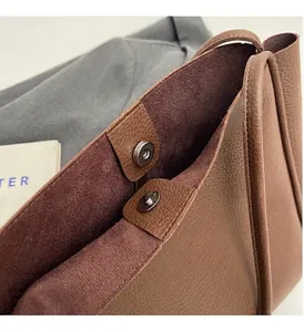 Detail of brown litchi grain leather bag showing magnetic closure and suede lining