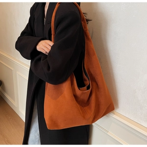 Detail of orange-brown suede tote bag showing large capacity and vintage texture on model
