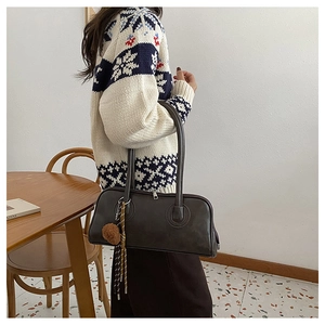 Detail of dark brown leather baguette bag with long handles and decorative charms