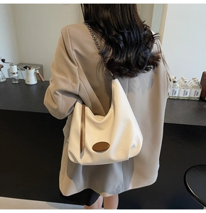 Detail of cream pebbled leather crescent bag with stylish woven chain shoulder strap