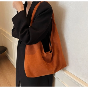 Grand sac cabas en daim rouge rouille porté par un mannequin montrant taille et texture